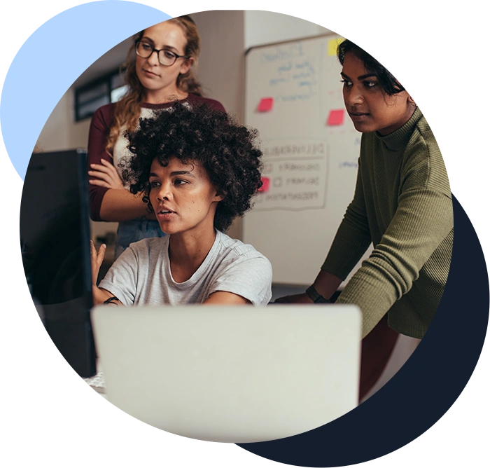 Color photo of three women at a computer, discussing strategies for transforming the business