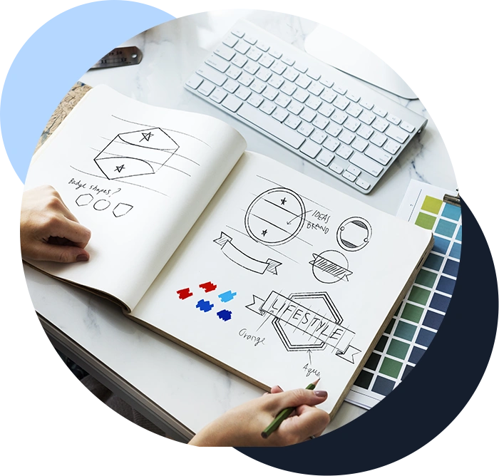 Color image of a person drawing logos and other branding graphics in an open notebook