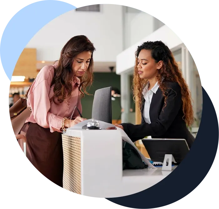 Hospitality worker smiling and talking with a client at front desk