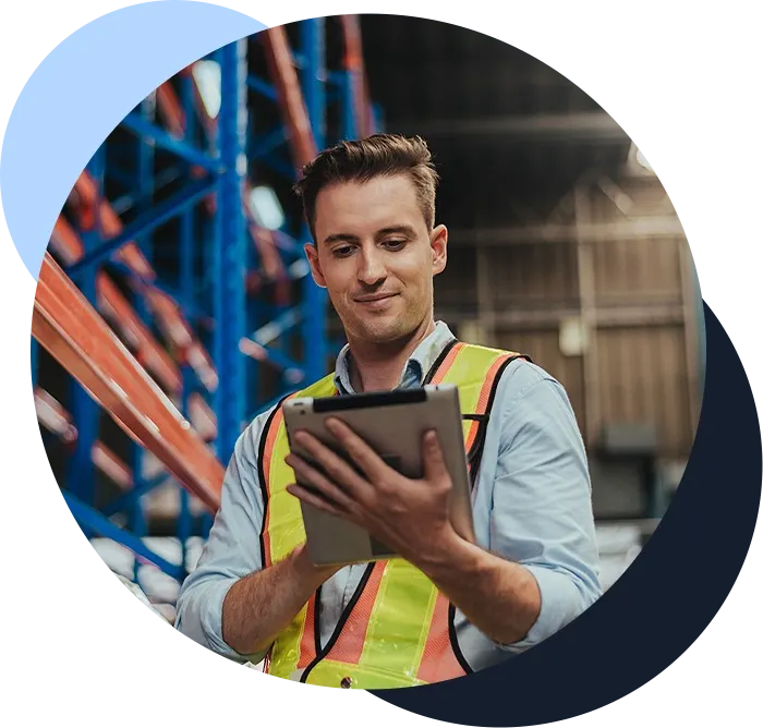 Man works on a tablet in warehouse location with shelving and storage in the background