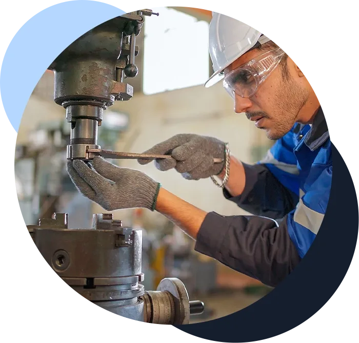 A man in a hard hat works on a piece of manufacturing equipment