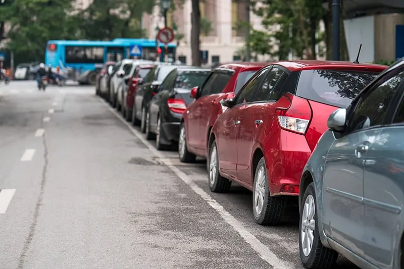 Cars tightly parallel parked along a curbside in a suburban town